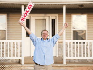 Happy homeowner celebrating the sale of their home with a 'Sold' sign, thanks to successful real estate transactions.