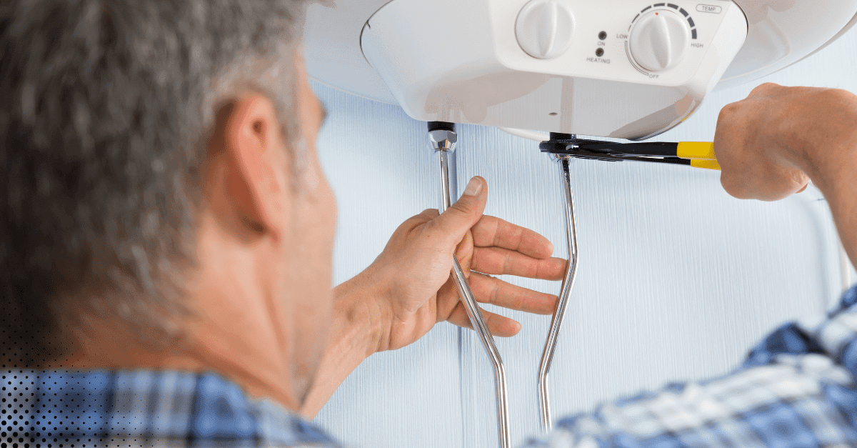 Technician tightening water heater connections with pliers.