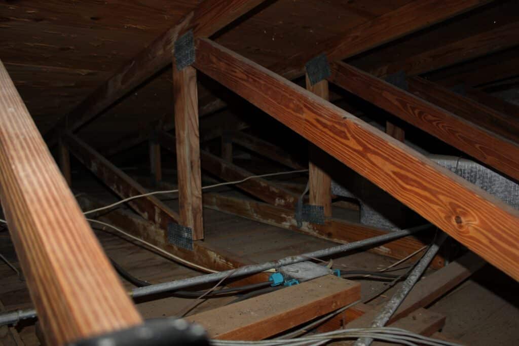 Attic interior showing wood roof trusses and exposed wiring during a home inspection in Fort Worth, TX