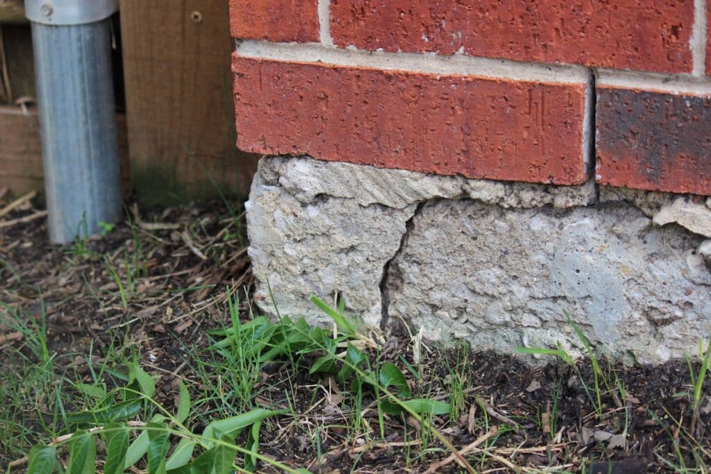 Cracked and deteriorating concrete foundation footing at base of brick exterior wall identified during a home inspection in Fort Worth, TX
